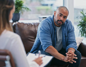 Young man looking thoughtful while sitting in session with his female therapist