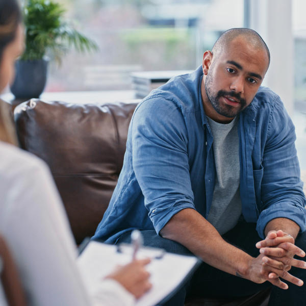 Young man looking thoughtful while sitting in session with his female therapist