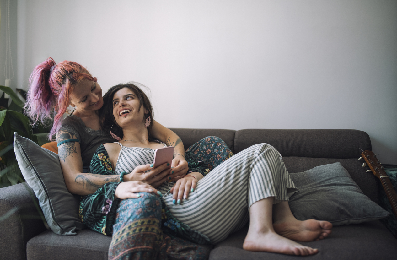 Two women cuddling at home on the sofa looking in love