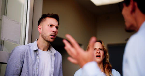 A group of three people arguing on the doorstep, shouting at each other.