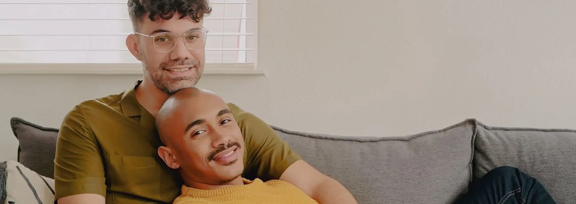 Two men cuddling at home on the sofa  looking in love