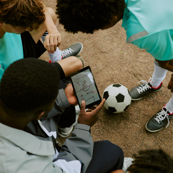 Multiethnic Teenagers Discussing Soccer Strategy Using Digital Tablet Outdoors