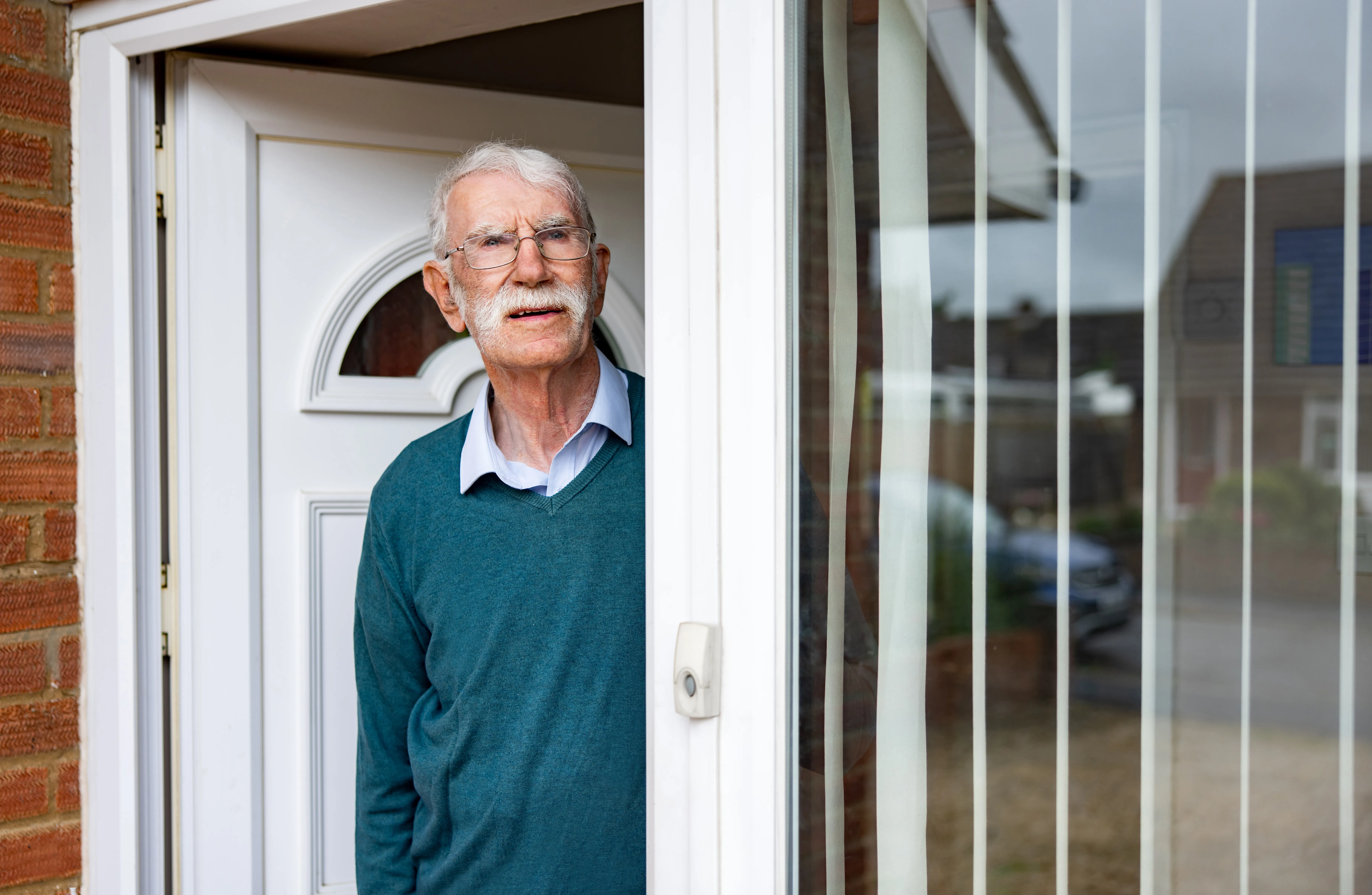 Old man stood at front door looking angry