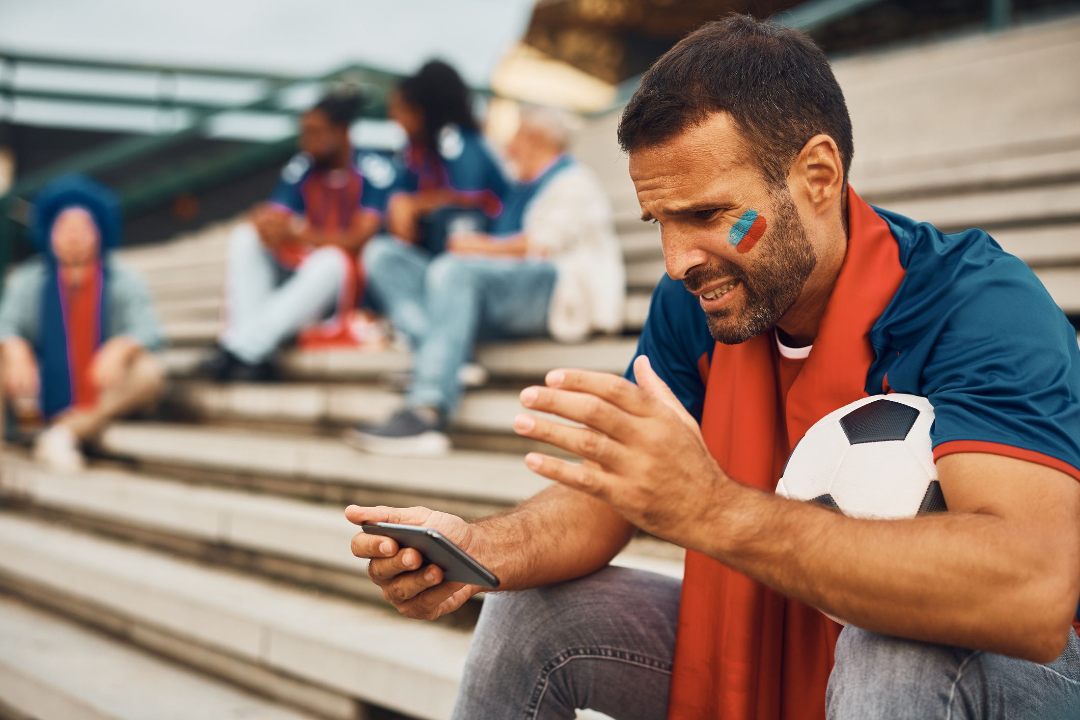 Disappointed Sports Fan Watching Soccer Game On Mobile Phone Outdoors