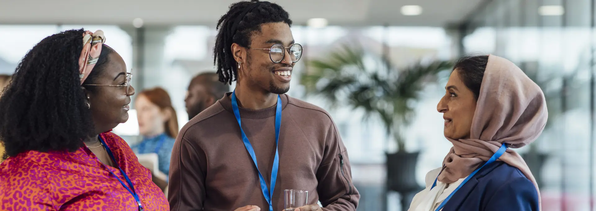 Black woman and Muslim women speaking to black man at the office.