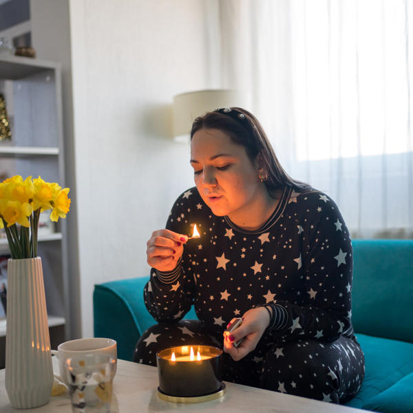 White woman at home lighting candle in her living room