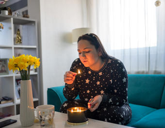 White woman at home lighting candle in her living room